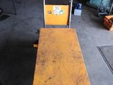 un banc jaune posé dans un garage, à côté d'un diable