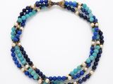 un collier de perles bleues et blanches muni d'un fermoir doré