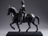 une statue antique en bronze représentant un homme à cheval, posée sur un socle en marbre