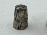 a silver thimble with a picture of a man and a dog on it