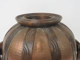 a large metal vase with a handle on a table