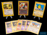 Plusieurs cartes Pokémon sont exposées sur une surface noire.