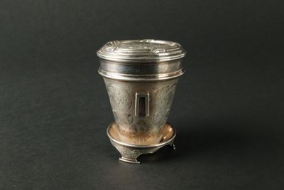 an antique silver salt shaker on a black background