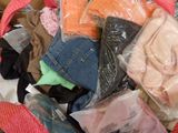 un tas de vêtements dans un sac posé sur un lit