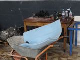 a wheelbarrow with a blue seat in a dirty room