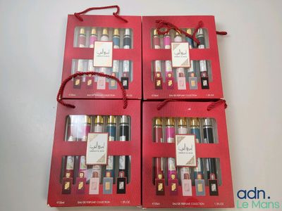 three red boxes with perfumes in them sitting on a table