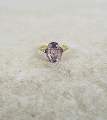 an image of a ring with a purple stone on a marble surface