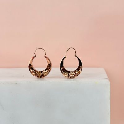 une paire de boucles d'oreilles en anneau en or posée sur un bloc de marbre