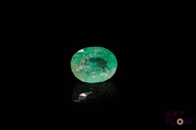 a close up of a green emerald on a black surface