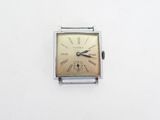 une petite montre carrée avec des chiffres romains sur le cadran