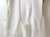 a white vest hanging on a hanger on a wall