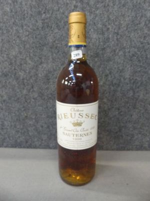 Des bouteilles de vin sont posées sur une table devant un fond gris.