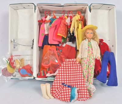 une poupée dans une valise remplie de vêtements et de chaussures