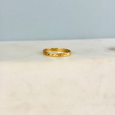 un gros plan d'une bague en or posée sur une surface en marbre