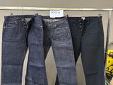 trois paires de jeans bleus suspendues à un portant dans un magasin