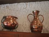 three copper vases sitting on a shelf in a room