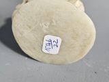 a small figurine sitting on a table with a sticker on it ' s back