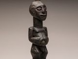 une sculpture en bois représentant un homme coiffé d'un chapeau