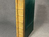 a green book sitting on top of a table next to a gray wall