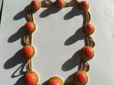 a close up of a bracelet with orange beads on a white surface