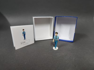 une petite figurine représentant un homme debout devant une boîte