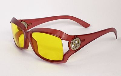 des lunettes de soleil rouges aux verres jaunes sur fond blanc