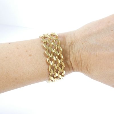 someone is wearing a gold bracelet with a chain on it