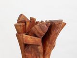 sculptures made of wood sit on a white pedestal against a white background