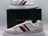 une paire de baskets blanches avec une bande rouge, noire et bleue sur le côté