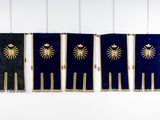 three blue and gold flags hanging on a white wall next to each other