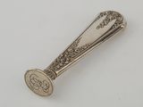 an antique silver spoon on a white surface with a flower design