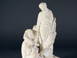 a white statue of a man kneeling down next to a woman