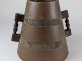 un vase marron muni d'une poignée en bois, posé sur une surface blanche