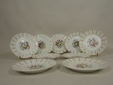four white plates with floral designs on them sitting on a table