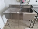 a stainless steel sink in the middle of a tiled floor