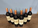 six bottles of wine are lined up on a wooden table