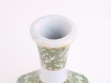 a green and white vase sitting on a white table