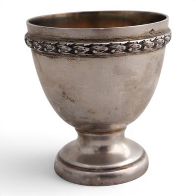 une vieille coupe en argent posée sur un socle en métal