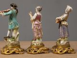 three figurines of women playing musical instruments on a table