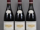 three bottles of red wine sit on a table in front of a gray background