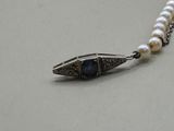 pearl necklace with a silver clasp and a blue glass bead