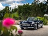 une voiture noire garée sur un parking orné de fleurs roses