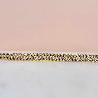 gros plan d'un bracelet en chaîne en or sur une surface blanche