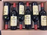 six bottles of red wine in a cardboard box on a table