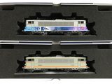 deux trains miniatures dans une boîte, posés sur une surface blanche