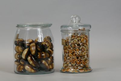 two glass jars with nuts in them on a white surface