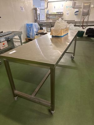 une grande table au milieu d'une cuisine, sur laquelle est posé un sac