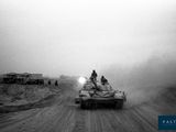 black and white photo of a tank driving down a dirt road