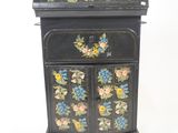 a small black cabinet with flowers painted on it