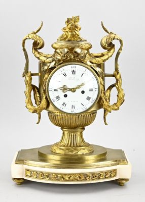 a gold clock that is sitting on a stand